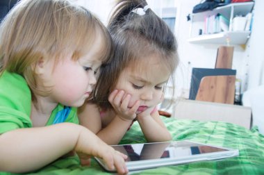 Çocuklar evde yatakta yatarken yastık üzerinde seyir. Çocuklar zaman harcama. Tablet bilgisayar kullanarak çocuklar