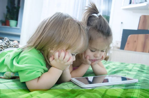 小女孩们躺在家里的床上看着垫子 孩子们的时间花 使用平板电脑的孩子 — 图库照片