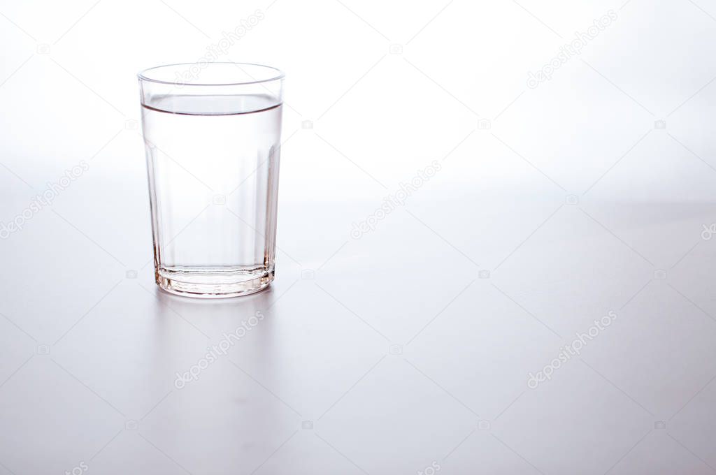 Water in transparent glass on gray background. purified fresh drink water on table