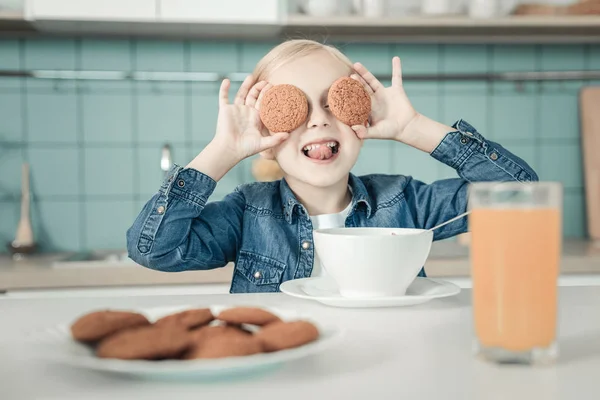 Playful girl holding biscuits near eyes — Stock Photo, Image