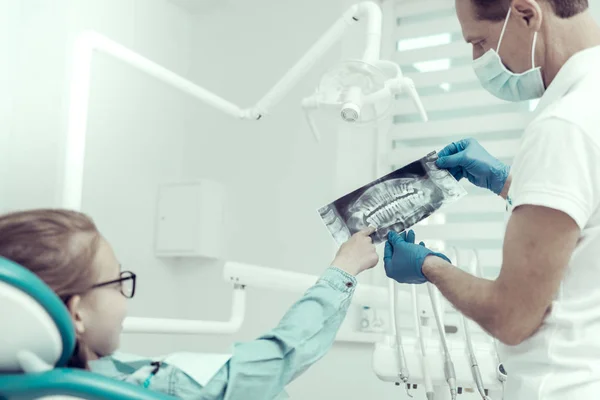 Pequeña paciente y su médico mirando los resultados de una radiografía — Foto de Stock