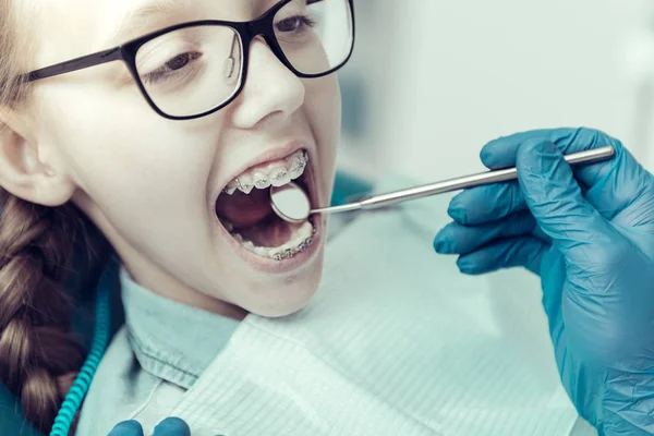 Маленька дівчинка сидить з стоматологічним дзеркалом в роті — стокове фото