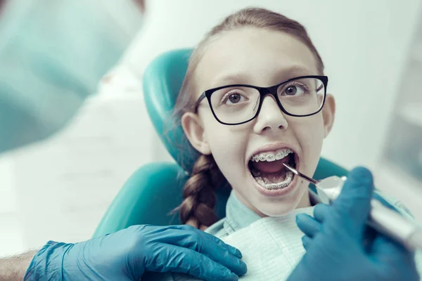 Diş hekimleri kabinde oturan gözlüklü küçük kız — Stok fotoğraf