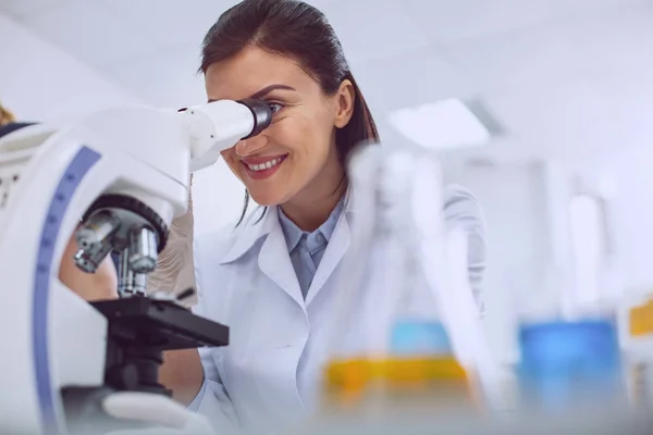 Joyful researcher looking into the microscope