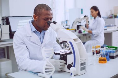 Onun mikroskopla çalışan erkek araştırmacı ilham