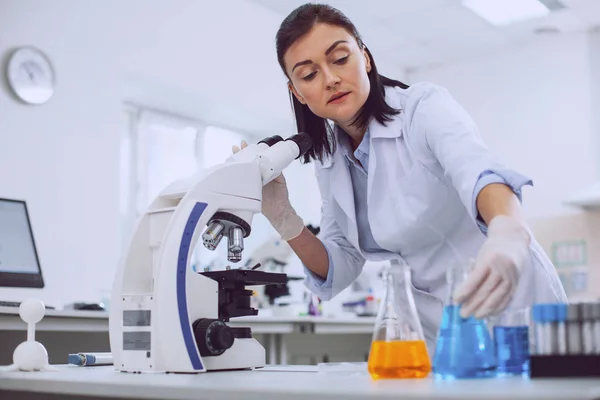 Bióloga femenina seria que trabaja con un microscopio — Foto de Stock