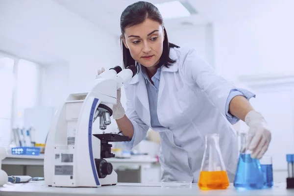 Bióloga femenina concentrada que trabaja con un microscopio — Foto de Stock