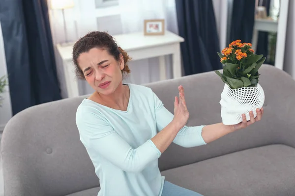 Young lady feeling unsure about an allergy provoking plant — Stock Photo, Image