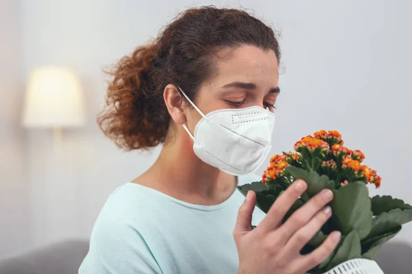 Chica joven sosteniendo una flor causando su alergia — Foto de Stock