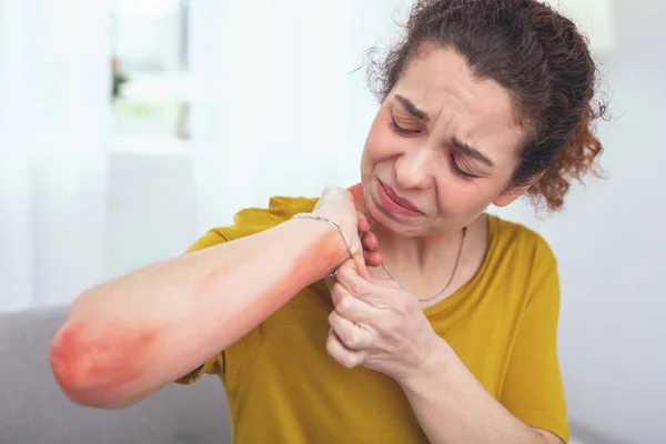 Jonge vrouw haar pijnlijke arm inspecteren — Stockfoto