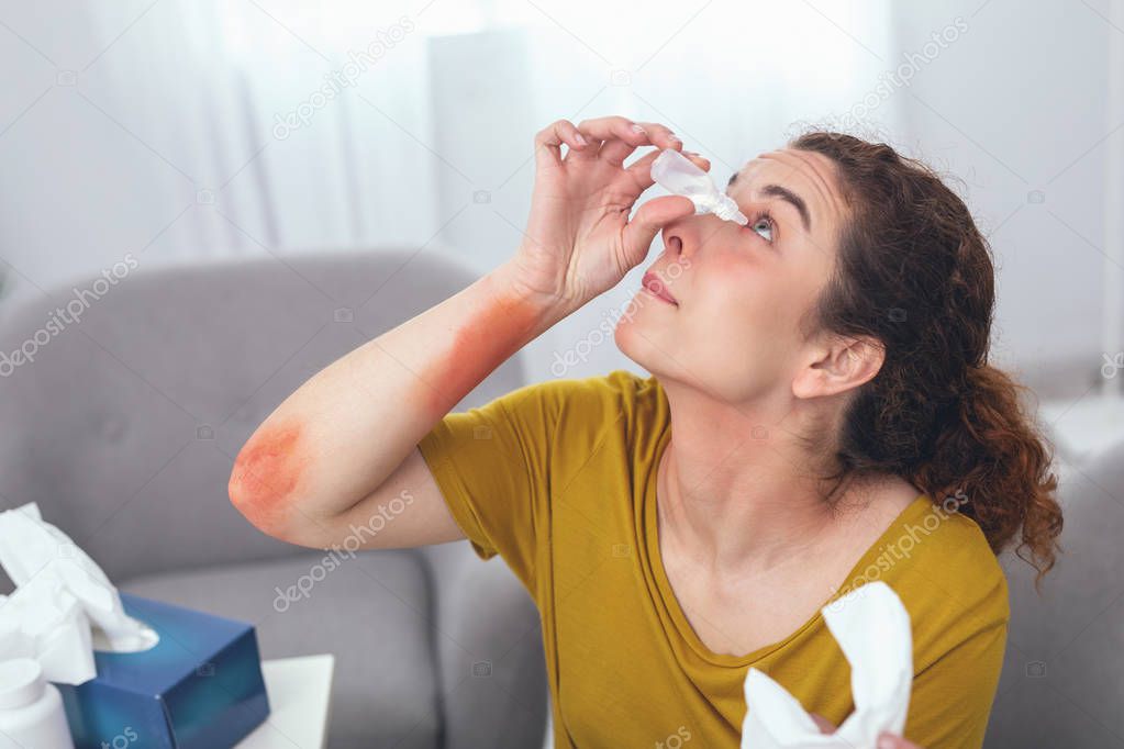 Adolescent woman trying to get eye drops into her eye
