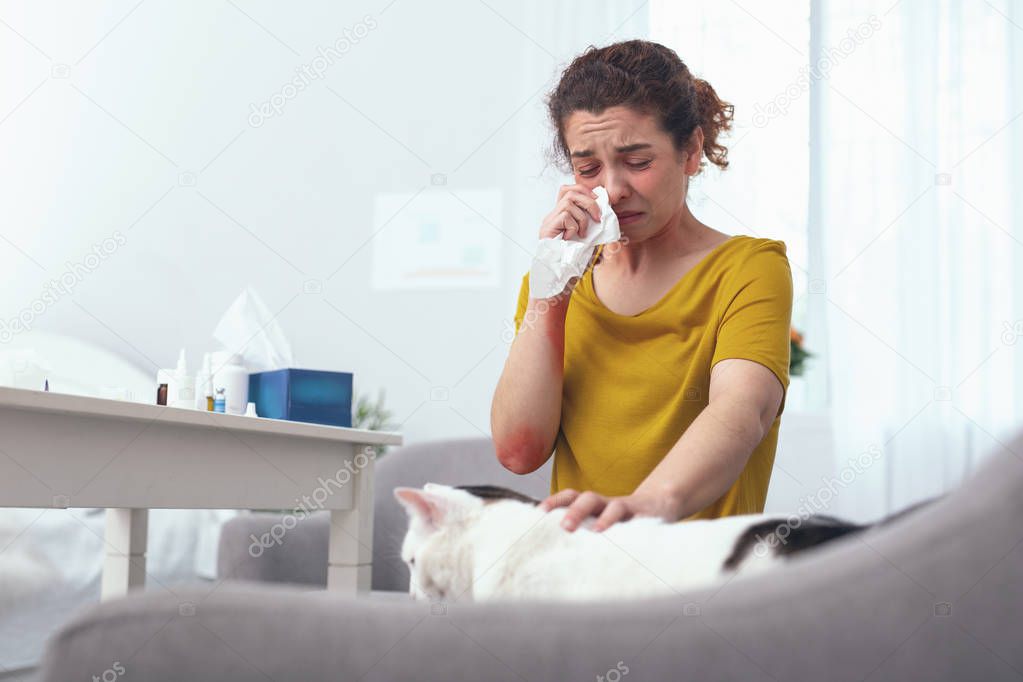 Young miserably looking woman suffering from runny nose