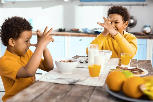 Veselý kluci thumbing jejich nosy na sebe během snídaně — Stock fotografie