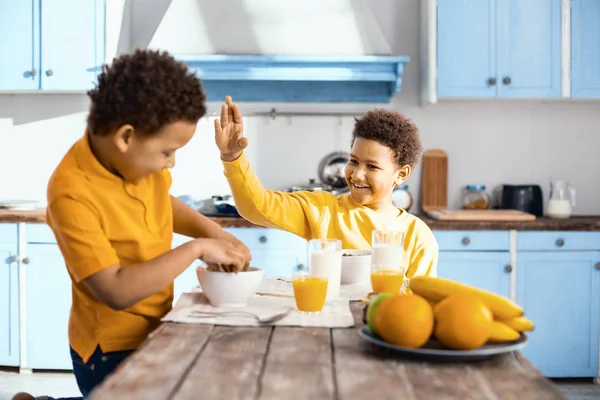 Agradable pre-adolescente queriendo abofetear a su hermano en el desayuno — Foto de Stock