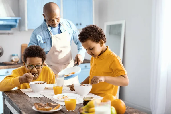 Lindos niños desayunando mientras su padre cocinaba tortilla — Foto de Stock