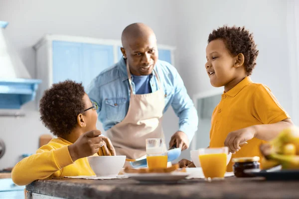 Lindos niños pequeños charlando con su padre mientras desayunan —  Fotos de Stock