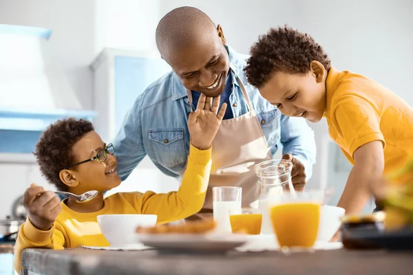 Веселий маленький хлопчик пестить батьків підборіддя на сніданок — стокове фото