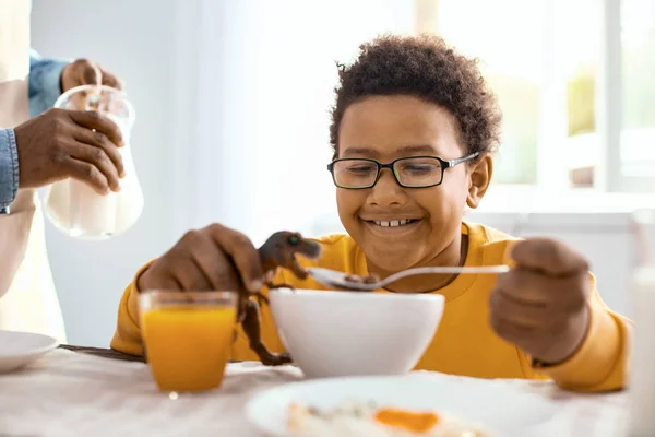 Fröhlicher Pre-Teenie-Junge füttert Spielzeug-Dinosaurier beim Frühstück — Stockfoto