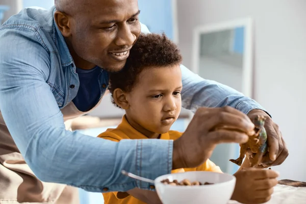 Gelukkig jonge vader voeding zijn zonen speelgoed dinosauriërs — Stockfoto