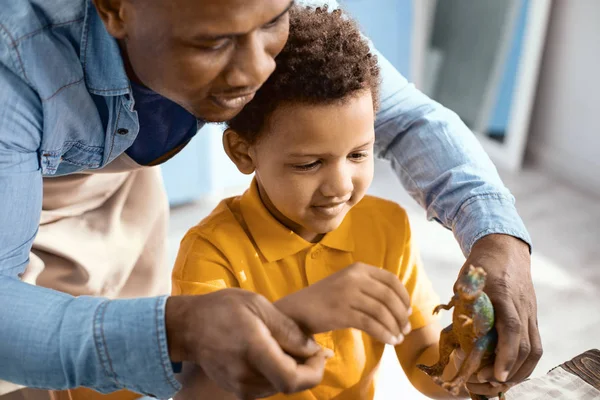 愉快的消遣 愉快的年轻父亲玩与他的小儿子在厨房和喂养玩具恐龙一起 — 图库照片