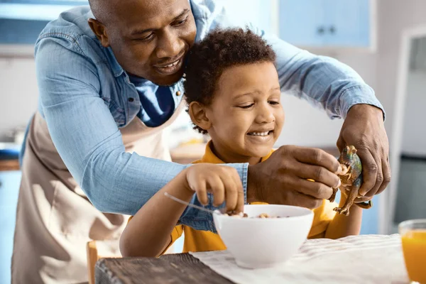 Alegre joven padre alimentación cereales a juguete de su hijo — Foto de Stock