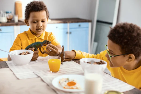 Kleine Jungen spielen in der Küche mit Spielzeug-Dinosauriern — Stockfoto