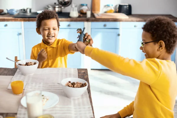 Fröhliche kleine Jungen im Kampf mit Spielzeug-Dinosauriern — Stockfoto