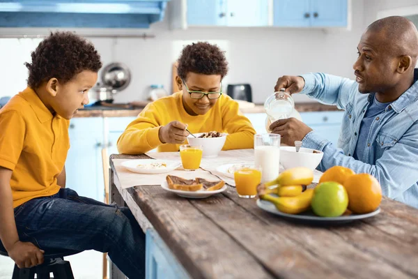 아침 식사 하는 동안 아들과 함께 채팅 하는 경쾌한 젊은 아버지 — 스톡 사진