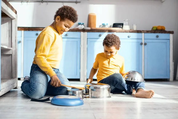 Fröhliche kleine Kinder trommeln in der Küche auf Töpfen — Stockfoto