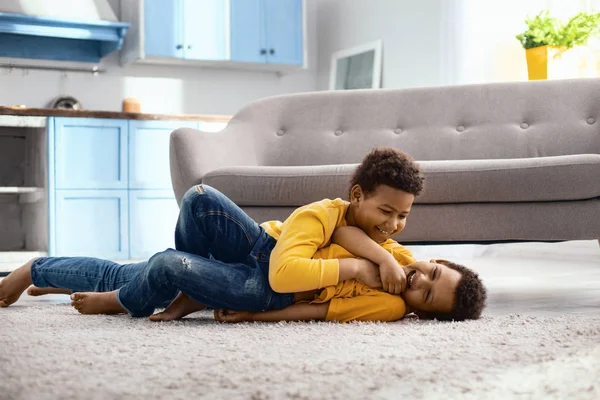 Vrolijk jongetje kietelen zijn jongere broer op verdieping — Stockfoto