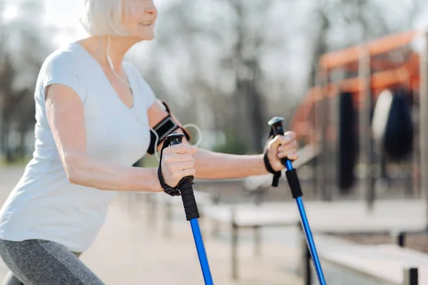 Glad woman using crutches while exercising