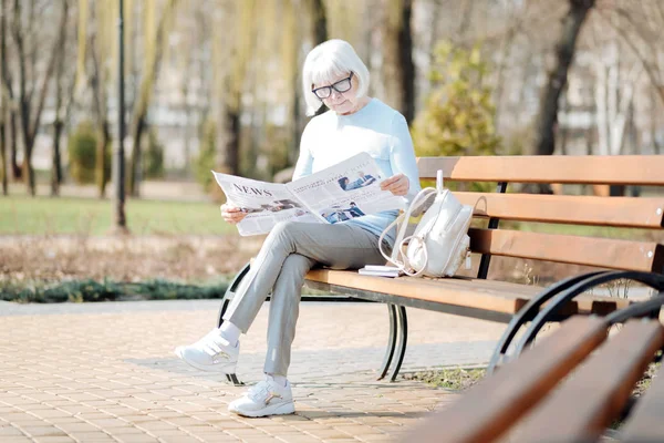 Konzentrierte alte Frau liest Zeitung — Stockfoto