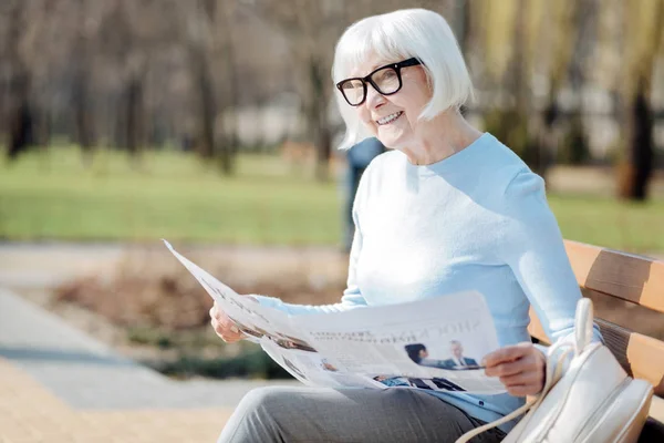 Mulher idosa exuberante lendo um jornal — Fotografia de Stock