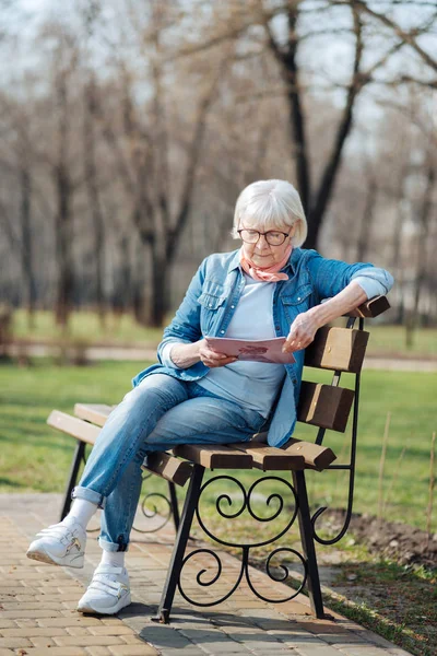 Серйозна стара жінка читає журнал — стокове фото
