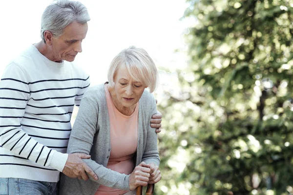 Keep fit. Serious old man standing in semi position and bowing head while supporting his wife