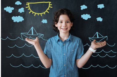 Pozitif çocuk gülümseyen ve denizdeki gemiler hakkında düşünürken