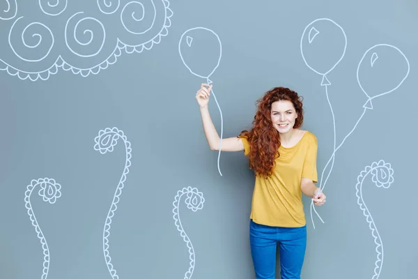 Emocional madre sonriendo mientras sostiene globos para su hijo — Foto de Stock