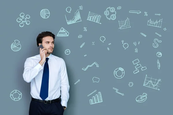 Calm businessman looking serious while having a phone talk — Stock Photo, Image