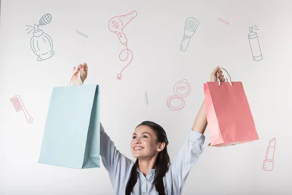 Heureuse jeune femme mettant les mains en l'air tout en tenant des sacs en papier — Photo