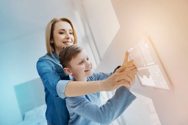 Sonriente chico presionando su dedo a la pantalla y su madre ayudándolo — Foto de Stock