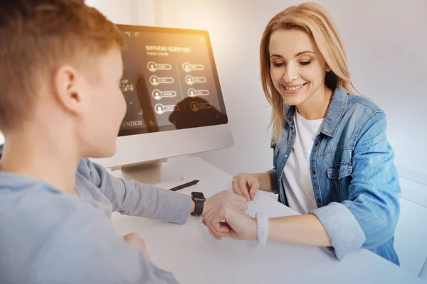 Mujer alegre sonriendo mientras mira el nuevo reloj inteligente — Foto de Stock