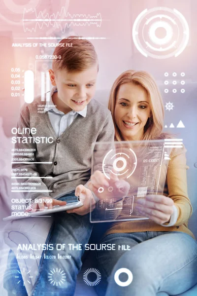Emotional programmer holding a transparent gadget and her curious child looking