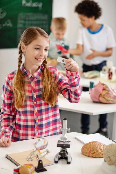 Chica encantada positiva sosteniendo una diapositiva del microscopio — Foto de Stock