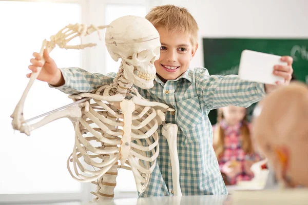 Χαρούμενα ωραίο αγόρι λαμβάνοντας μια φωτογραφία με τον σκελετό — Φωτογραφία Αρχείου