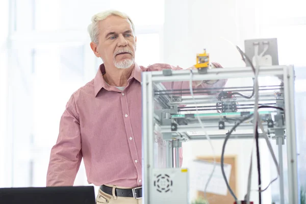 Charmant vieil homme contrôlant le travail de l'imprimante 3D — Photo