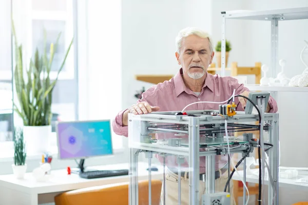 Agradável homem sênior assistindo trabalho de impressora 3D — Fotografia de Stock