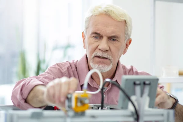 Uomo più anziano piacevole che cambia installazioni di stampante 3D — Foto Stock