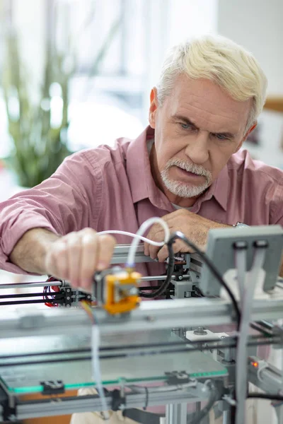 Bonito homem idoso ajustando extrusora de impressora 3D — Fotografia de Stock