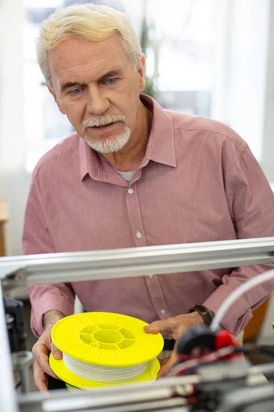 Hombre mayor encantador sosteniendo filamento para impresora 3D — Foto de Stock