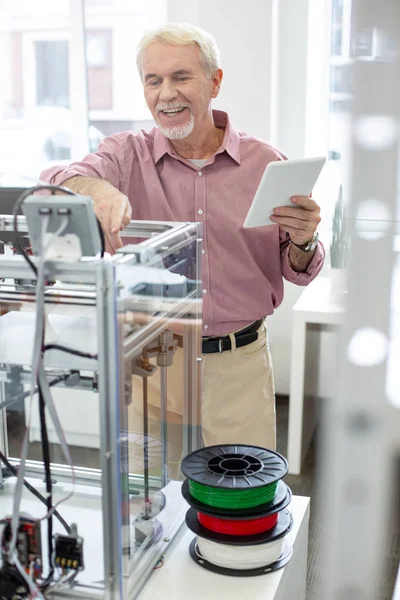 Joyful senior man learning how to use 3D printer